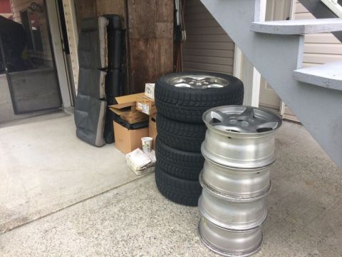 2002 Pontiac Grand Prix - A stack of four aluminum alloy wheels and a stack of four tires are leaning against a set of outdoor stairs. In the background, car seats a…