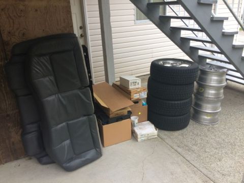 2002 Pontiac Grand Prix - Several car seats are stacked and leaning against a wooden door. Next to them are stacks of tires and car rims, along with some cardboard b…
