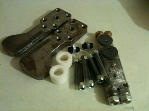 2002 Pontiac Grand Prix - A collection of custom metal parts and hardware are laid out on a light-colored surface. The parts include two large, shaped metal brackets…