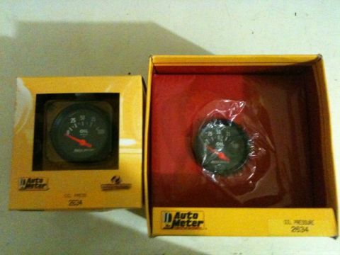 2002 Pontiac Grand Prix - Two Auto Meter oil pressure gauges are shown in their yellow packaging. One gauge is visible through the window of its box, while the other…