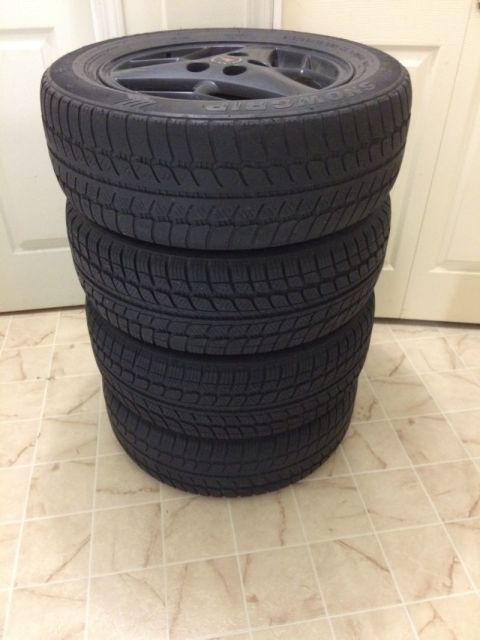 2002 Pontiac Grand Prix - A stack of four black tires with visible tread patterns is shown. The top tire is mounted on a dark gray rim with a multi-spoke design.