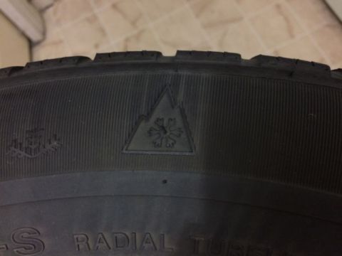 2002 Pontiac Grand Prix - A close-up of a tire shows the sidewall with a snowflake symbol inside a triangle, indicating it is a winter tire. Text on the tire include…
