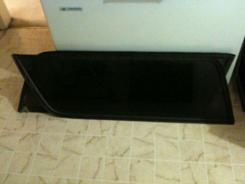 2002 Pontiac Grand Prix - Two black car window tint panels are laid out on a tiled floor in front of a white appliance. The panels are rectangular with a curved corn…