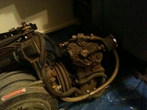2002 Pontiac Grand Prix - A close-up view shows a rusty engine component, possibly an air compressor, with hoses and a small filter attached. A large spool of cable…