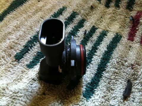 2002 Pontiac Grand Prix - A black automotive part with a red O-ring is shown resting on a carpeted surface with green and white stripes. The part appears to be a sen…