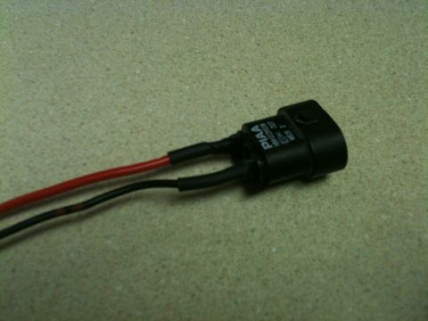 2002 Pontiac Grand Prix - A close-up shot shows a black electrical connector with red and black wires attached. The connector has white text that reads "PIAA" and ot…