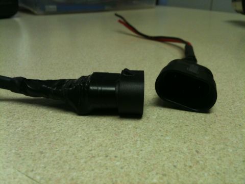 2002 Pontiac Grand Prix - A close-up shot shows two black electrical connectors, one with exposed wires taped to its base, lying on a speckled countertop.