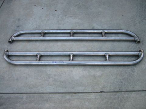 1985 Ford Bronco - Two metal rock sliders are shown laid out on a concrete surface.