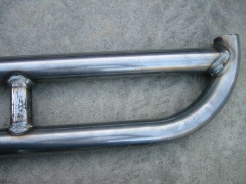 1985 Ford Bronco - Custom metal rock sliders, likely for an off-road vehicle, are shown against a concrete surface.