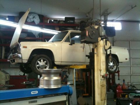 2002 Pontiac Grand Prix - A white pickup truck is raised on a hydraulic lift in a garage. A shiny metal wheel is placed on a blue piece of equipment in the foregroun…