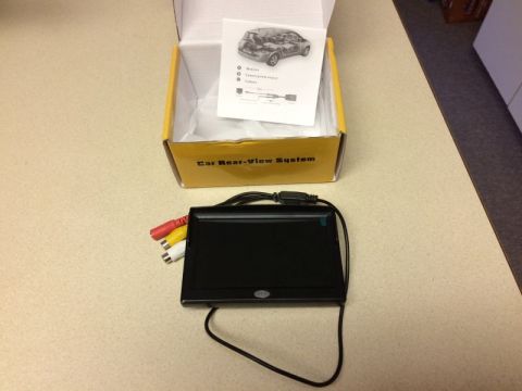 2002 Pontiac Grand Prix - A car rear-view system is displayed, including a monitor with RCA cables and a yellow box with instructions inside. The box is labeled "Car…