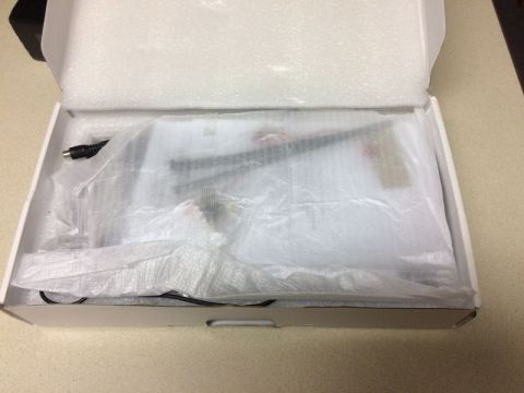 2002 Pontiac Grand Prix - A white box is open and contains a white electronic device wrapped in plastic and foam padding. A black power cord with a circular connecto…