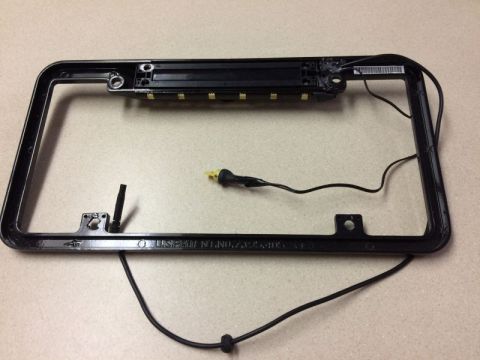 2002 Pontiac Grand Prix - A black license plate frame with integrated LED lights and wiring is shown against a light-colored, textured surface. The frame has visible…