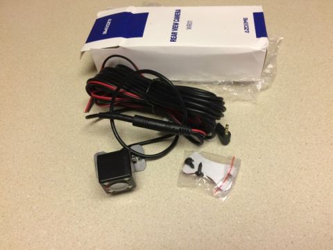 2002 Pontiac Grand Prix - A rear view camera and its accessories are laid out on a speckled countertop next to its packaging. The packaging is white with blue accent…