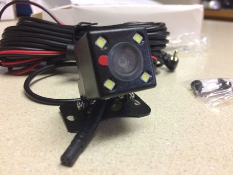 2002 Pontiac Grand Prix - A black backup camera with four LED lights and a red indicator is shown with its wiring harness and mounting bracket. A small bag of screws…