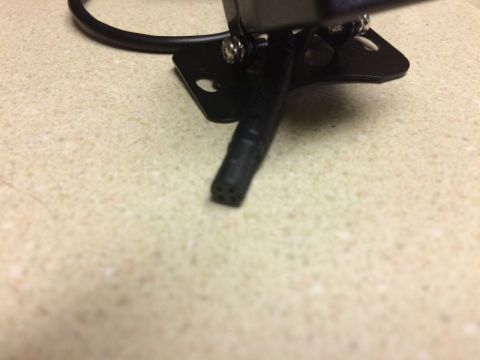 2002 Pontiac Grand Prix - A close-up of a black camera connector with multiple pins is shown attached to a black mounting bracket. The connector is plugged into a ca…