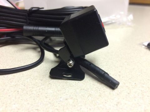 2002 Pontiac Grand Prix - A black backup camera with a mounting bracket and attached cables is shown on a speckled countertop.