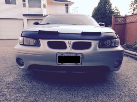2002 Pontiac Grand Prix - Front view of a silver Pontiac Grand Prix with a black car bra covering the hood and front bumper. The car is parked on a driveway in front…
