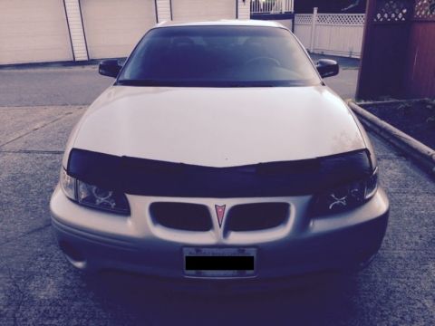 2002 Pontiac Grand Prix - A front-facing view of a silver Pontiac Grand Prix with a black bra installed over the front bumper and hood. The car is parked on a paved…