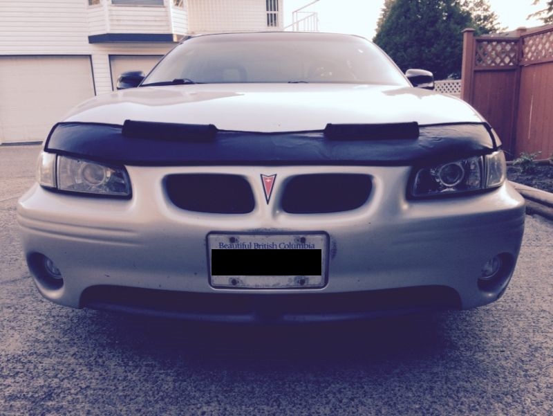 Silver Pontiac Grand Prix front view with black car bra and license plate.
