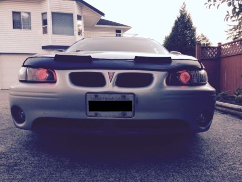 2002 Pontiac Grand Prix - Front view of a silver Pontiac Grand Prix with a black car bra. The vehicle is parked in a driveway in front of a white house.