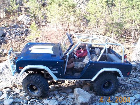 1977 Ford Bronco - A blue 1977 Ford Bronco navigates a rocky trail with a driver behind the wheel.
