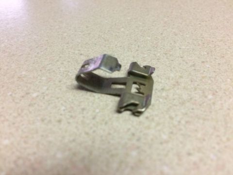 2002 Pontiac Grand Prix - A close-up, angled shot shows a small, metallic clip with a U-shaped design and two small prongs. The clip is positioned on a speckled coun…