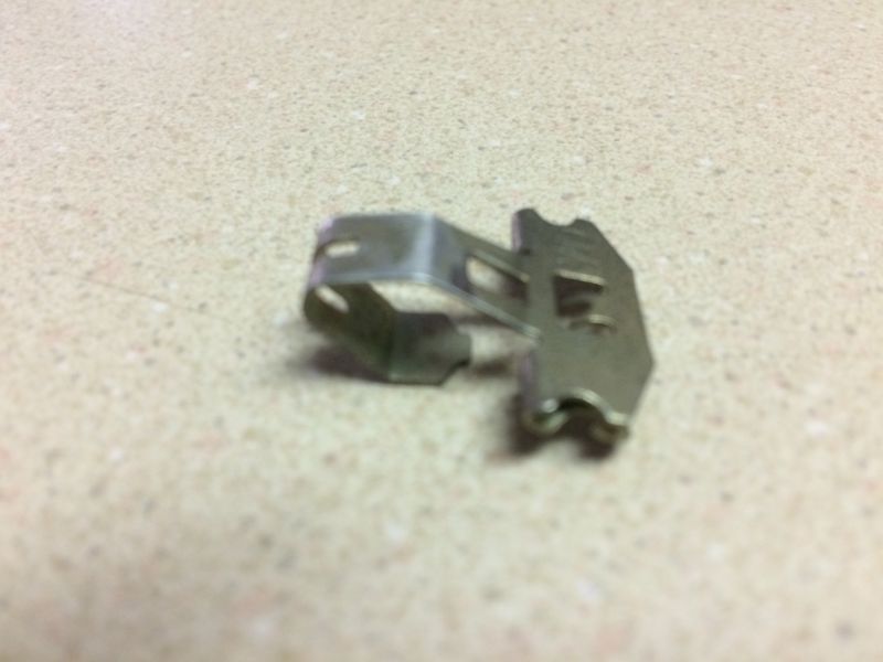 Silver metal spring clip on a speckled surface