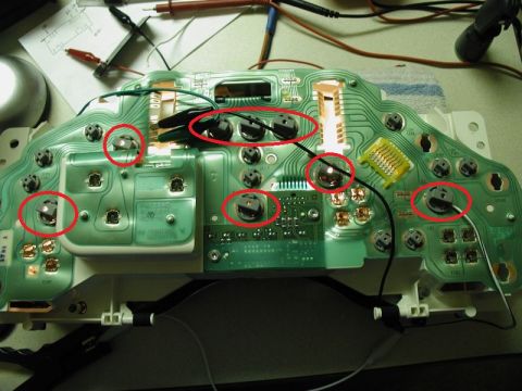 2002 Pontiac Grand Prix - The back of a green circuit board, likely from a car's instrument cluster, is shown with several components circled in red. Some wires and…