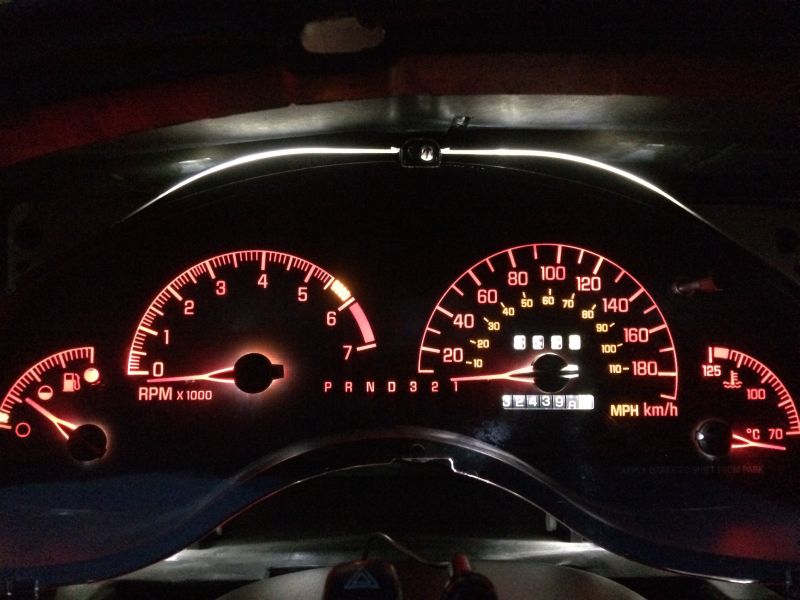 Illuminated dashboard of a 2002 Pontiac Grand Prix at night, showing tachometer, speedometer, and odometer.