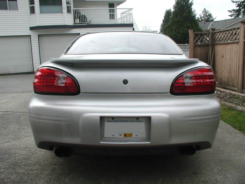 Rear view of a silver 2002 Pontiac Grand Prix with a spoiler and dual exhaust pipes.