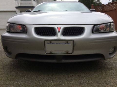 2002 Pontiac Grand Prix - The front view of a silver Pontiac Grand Prix shows its headlights, grille with the Pontiac emblem, and a "Beautiful British Columbia" lice…