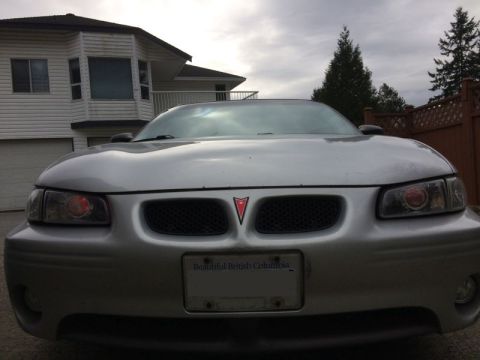 2002 Pontiac Grand Prix - The front of a silver 2002 Pontiac Grand Prix is shown parked in front of a house. The car has a license plate that reads "Beautiful Britis…