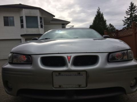2002 Pontiac Grand Prix - The front view of a silver Pontiac Grand Prix is shown parked in front of a house. The car has a license plate that reads "Beautiful Britis…