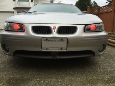2002 Pontiac Grand Prix - Front view of a silver Pontiac Grand Prix with red halo headlights and a British Columbia license plate. The car is parked outdoors on a we…