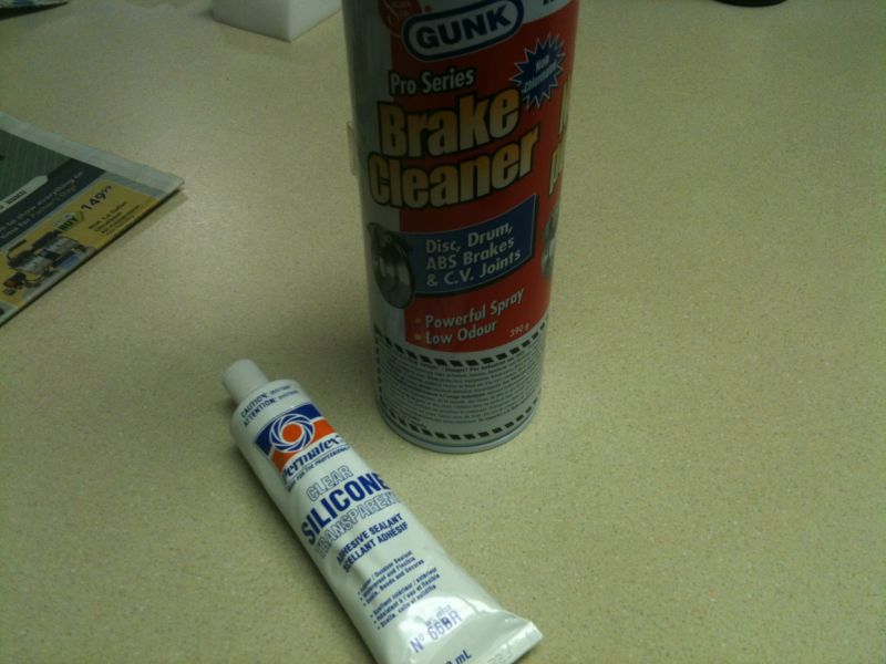 Can of brake cleaner and tube of silicone sealant on a countertop.