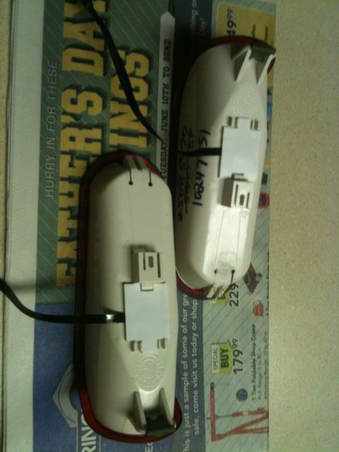 2002 Pontiac Grand Prix - Two clear taillight assemblies are shown laid out on a Father's Day newspaper advertisement. Each assembly has a white plastic housing with…