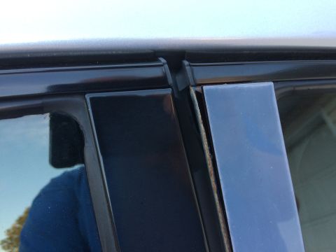 2002 Pontiac Grand Prix - Close-up view of the B-pillar trim on a dark-colored vehicle, showing some rust developing on the edge of the trim piece.