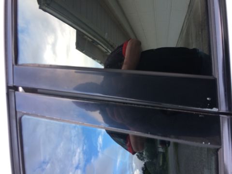 2002 Pontiac Grand Prix - Reflection in the window of a person wearing a red shirt and black pants, leaning against a building.