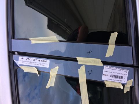 2002 Pontiac Grand Prix - Two protective film labels are taped to the side of a vehicle window. One label reads "PROTECTIVE FILM" and the other has "100% SATISFACTIO…