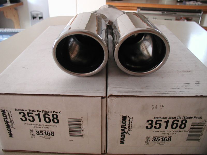 Two shiny chrome exhaust tips on top of their boxes.