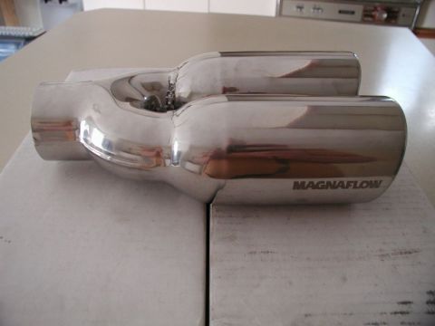 2002 Pontiac Grand Prix - A polished stainless steel Magnaflow exhaust tip is shown from a side angle, resting on a white surface. The tip has a dual outlet design w…