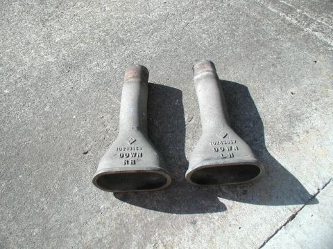 2002 Pontiac Grand Prix - Two exhaust tips with part numbers and 'DOWN RH' and 'DOWN LH' stamped on them rest on a concrete surface.