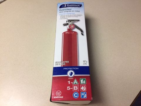 2002 Pontiac Grand Prix - A red Garrison fire extinguisher in its original packaging sits on a desk. The box is primarily white with red and blue accents and feature…