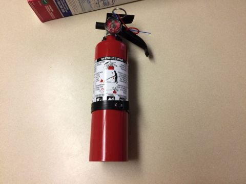2002 Pontiac Grand Prix - A red fire extinguisher is shown on a light-colored surface. The fire extinguisher has instructions printed on its side in English and Fren…