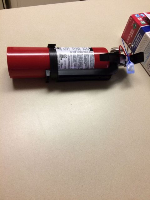 2002 Pontiac Grand Prix - A red fire extinguisher is shown lying on a light-colored surface, possibly a desk or countertop. A small cardboard box is partially visibl…