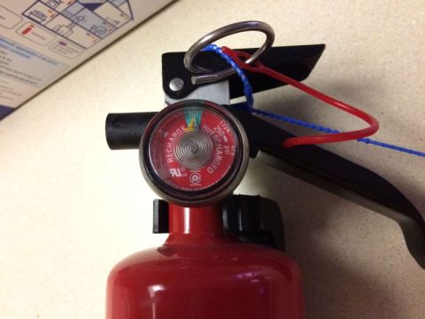 2002 Pontiac Grand Prix - A close-up shot of a red fire extinguisher with a pressure gauge. The gauge indicates the extinguisher is fully charged, and safety seals a…