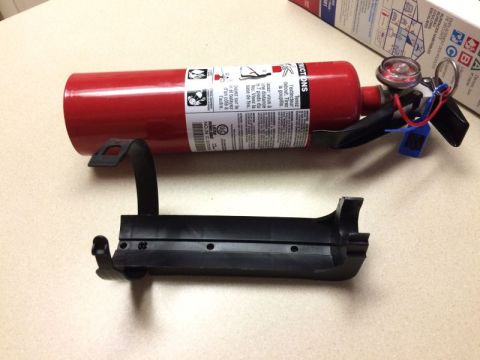 2002 Pontiac Grand Prix - A red fire extinguisher is shown lying on its side next to its black mounting bracket. The fire extinguisher has a pressure gauge and a saf…