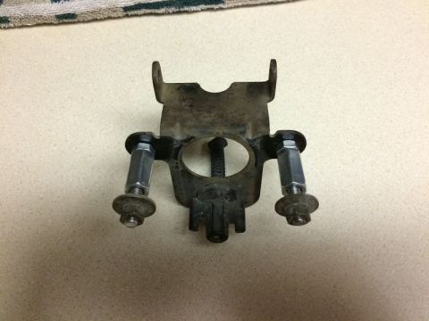 2002 Pontiac Grand Prix - A close-up view of a metal bracket with two bolts and nuts attached, possibly a part from a car's engine bay. The bracket is dirty and show…