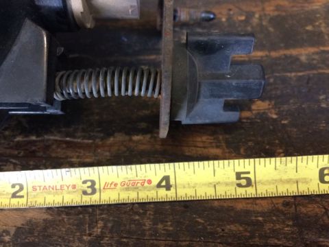 2002 Pontiac Grand Prix - A close-up view shows a metal spring attached to a black plastic component, with a yellow measuring tape indicating a length of approximate…